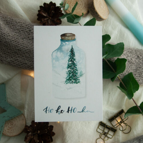Weihnachtspostkarte „HO HO HO“ zeigt eine handgezeichnete Illustration eines festlichen Tannenbaums in einer Glasflasche, umgeben von einer winterlichen Schneelandschaft. Gestaltet von Frau Feierlich