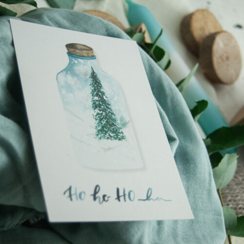 Weihnachtspostkarte „HO HO HO“ zeigt eine handgezeichnete Illustration eines festlichen Tannenbaums in einer Glasflasche, umgeben von einer winterlichen Schneelandschaft. Gestaltet von Frau Feierlich