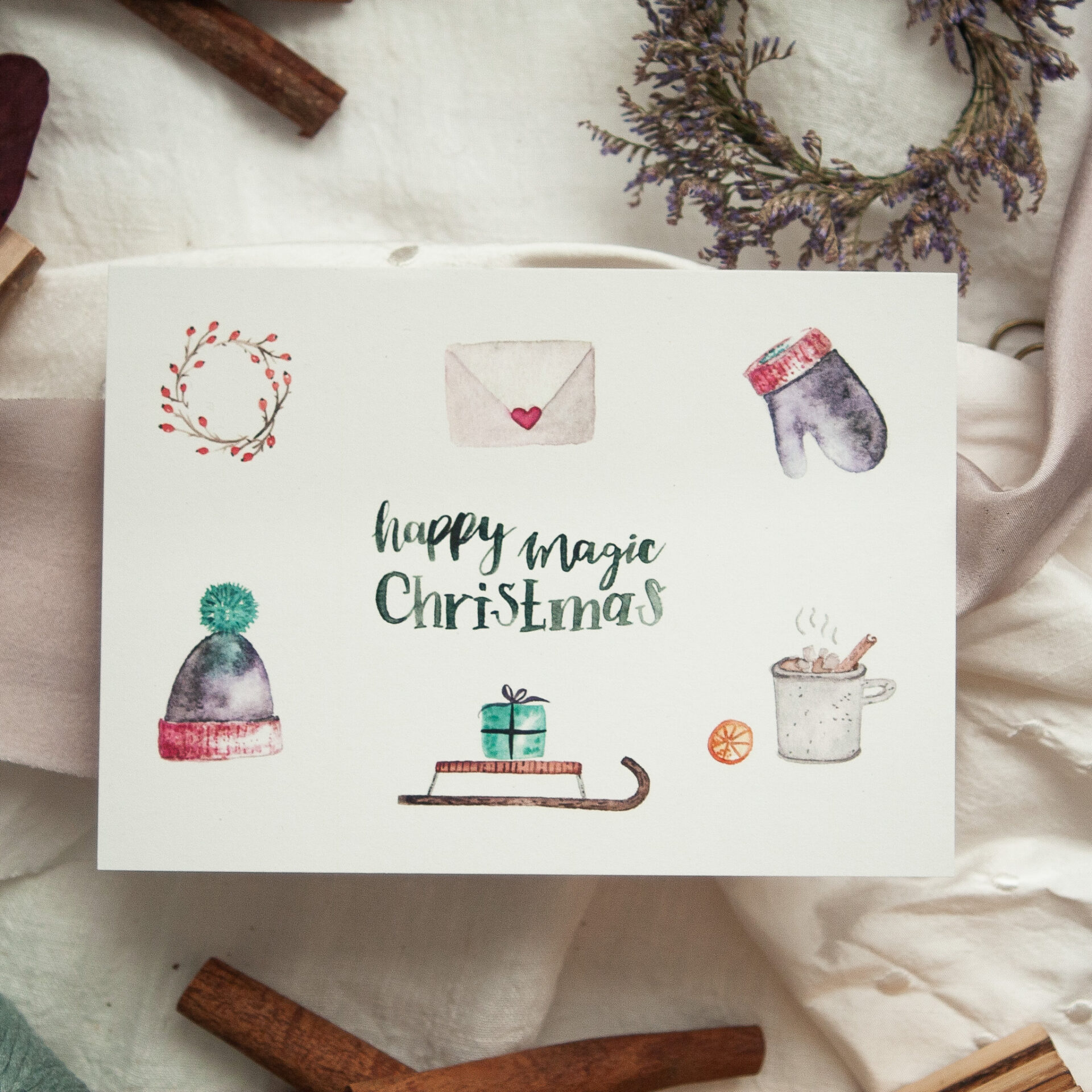 Handgemalte Weihnachtspostkarte "Happy Magic Christmas" mit winterlichen Aquarellillustrationen – Mütze, Handschuh, Geschenk auf Schlitten, Tasse Kakao, gestaltet von Frau Feierlich