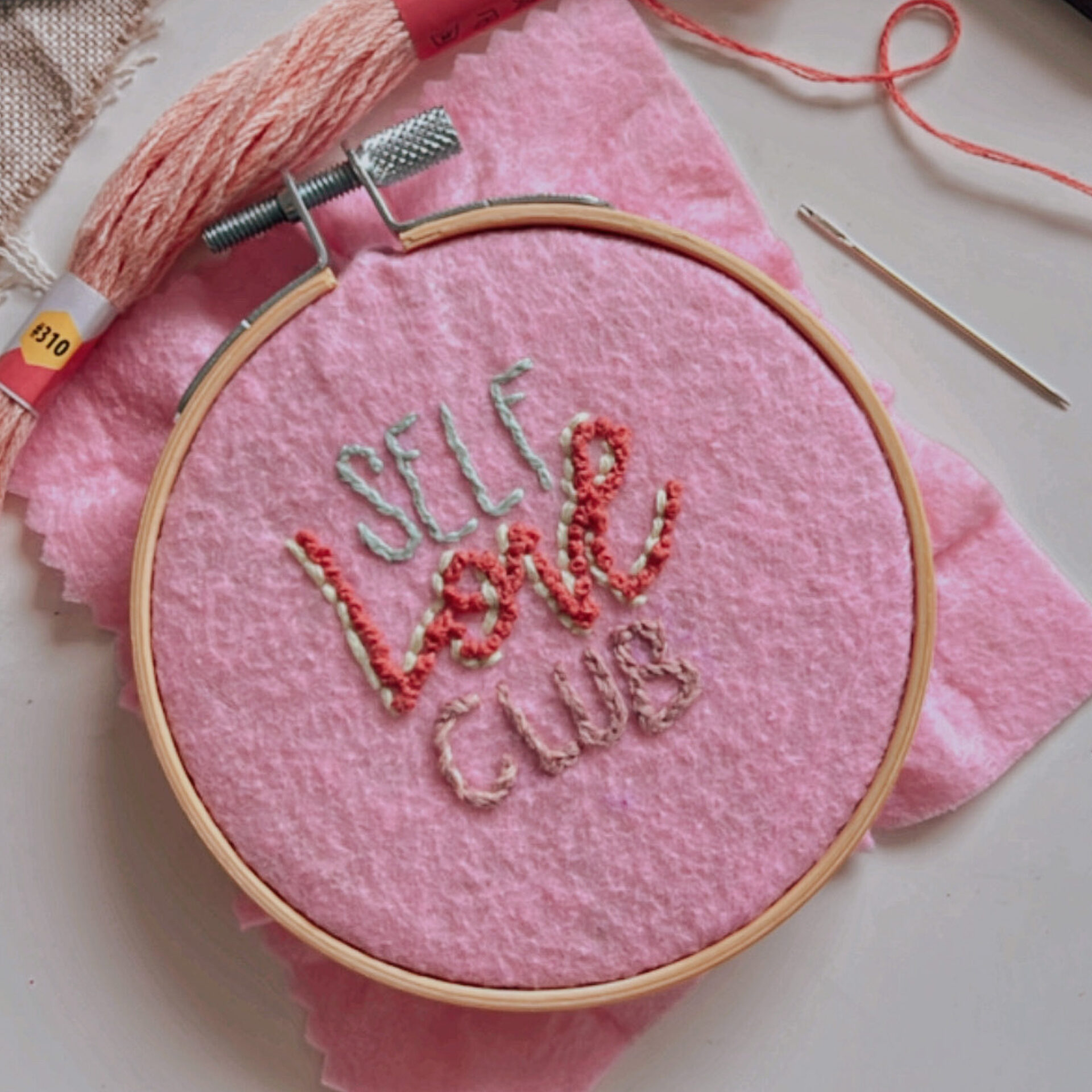 Statement Stickerei Workshop mit Frau Feierlich, Schrift Sticken mit Nadel und Faden, Self Love Club gestickt auf rosa Hintergrund